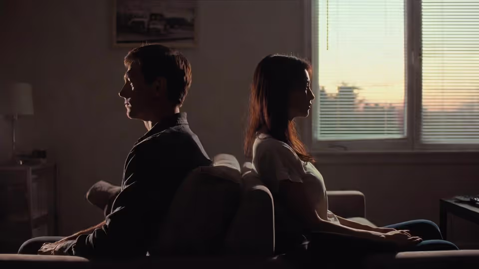 An emotionally distant couple sitting on the same sofa