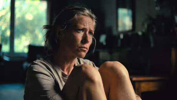 Adult sitting alone indoors appearing reflective and tense